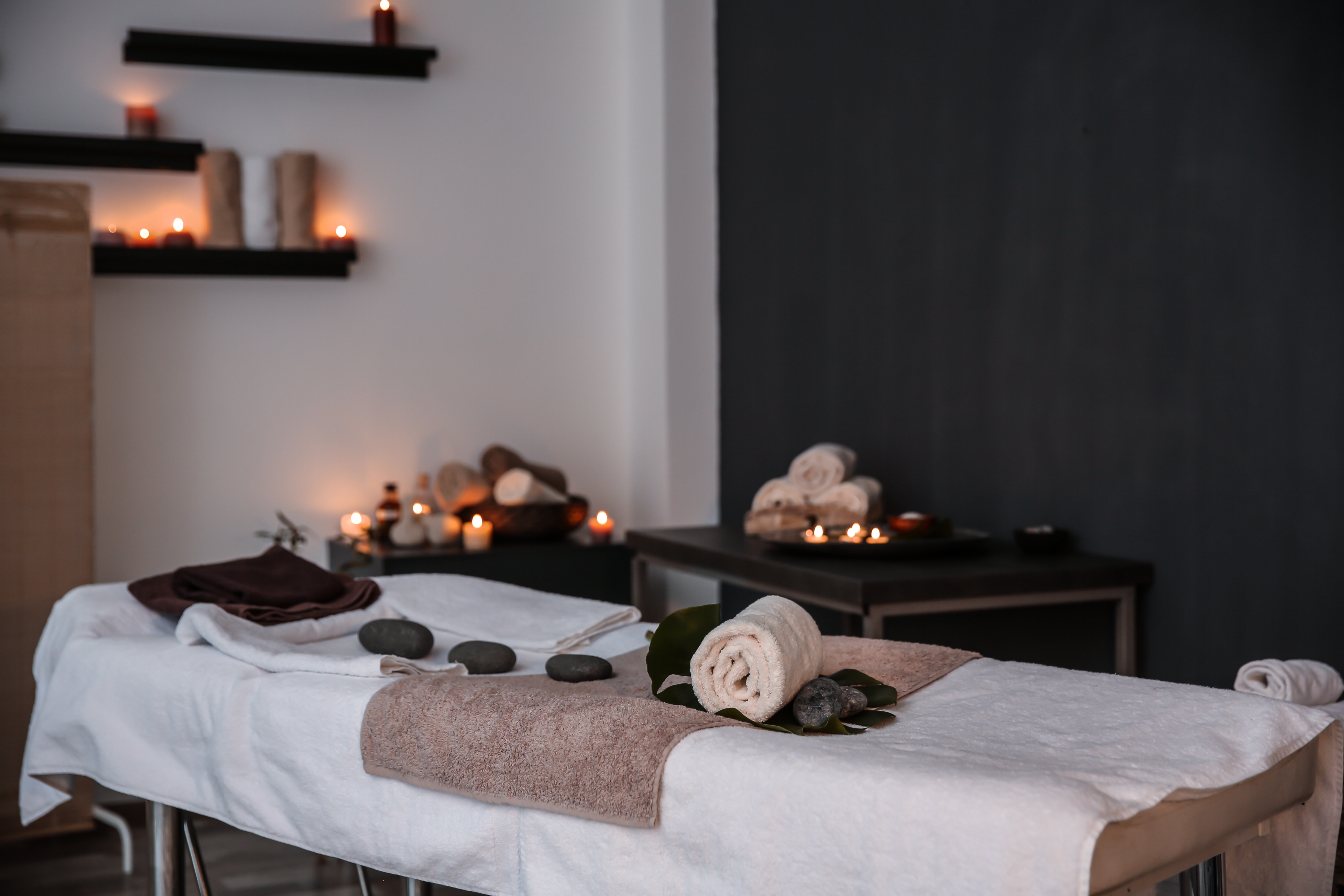 massage room with the curtains drawn, light coming from candles placed all throughout the room