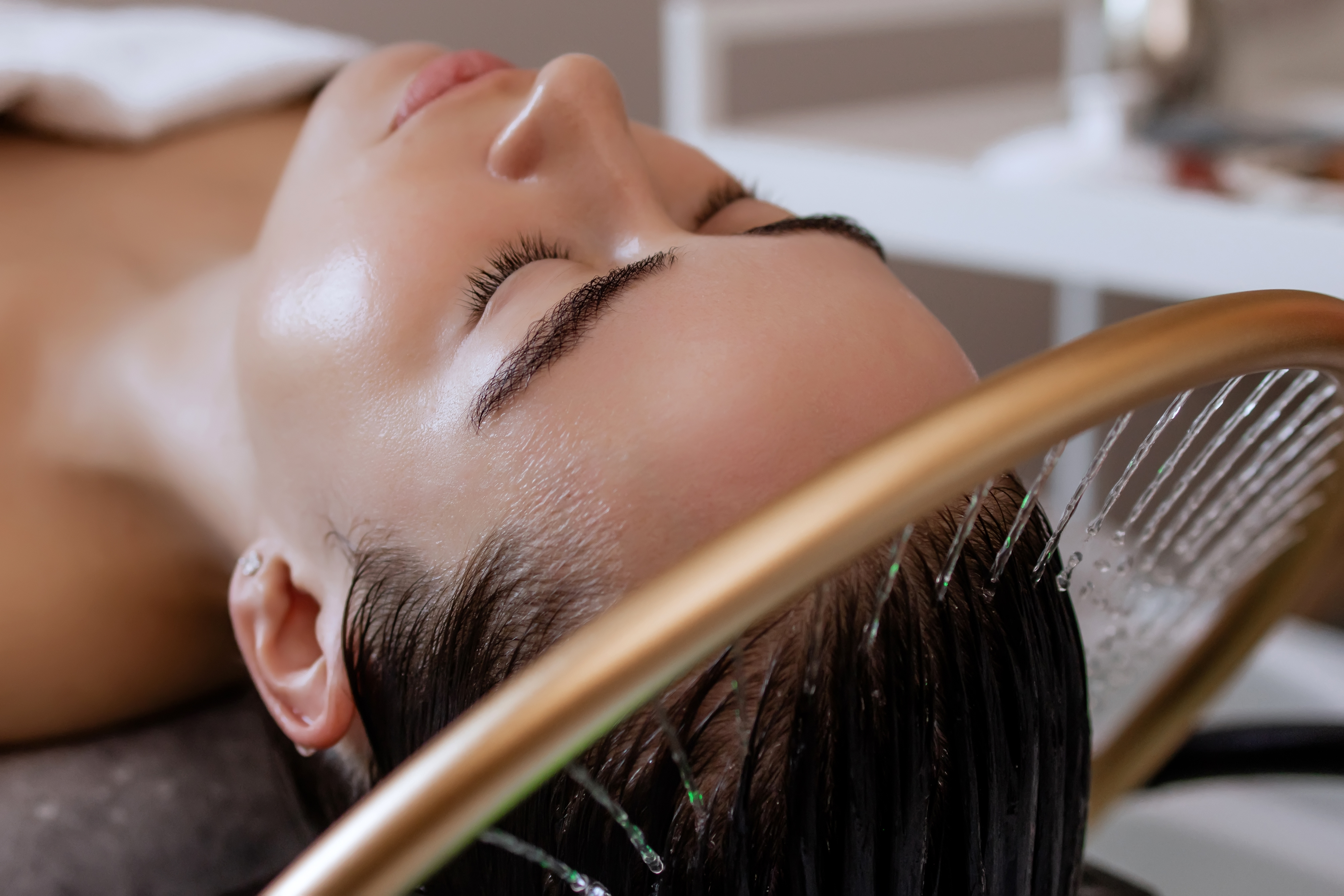image of a woman getting a hair rinse while laying down on a massage bed