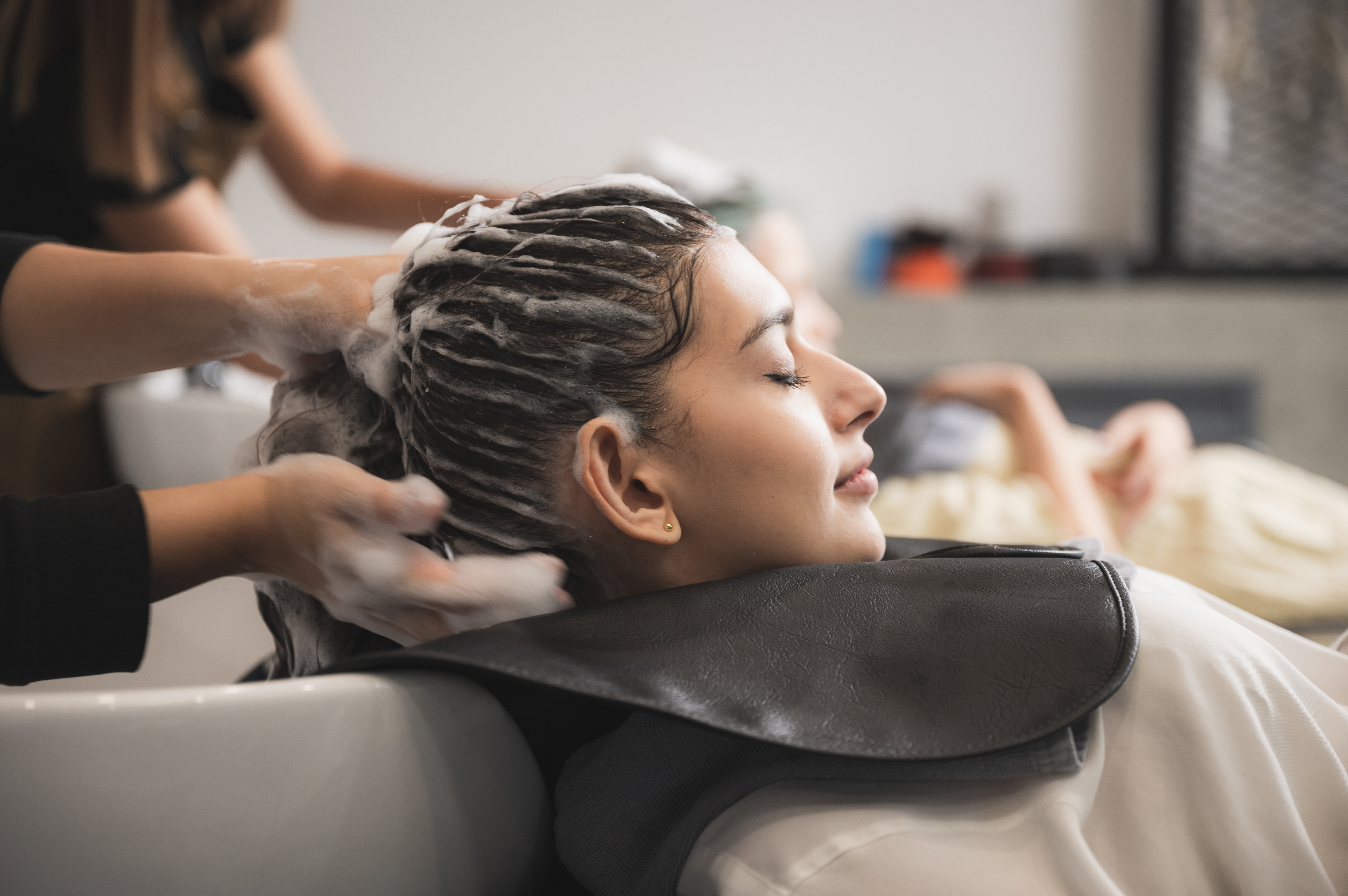 woman in massage chair from side profile, getting shampoo massaged into her hair.